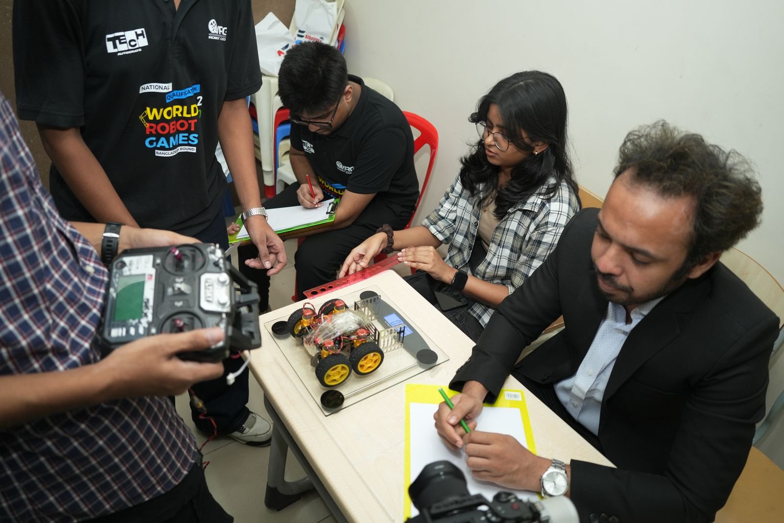A judge takes notes as a team operates its remote-controlled robot on the scoring desk