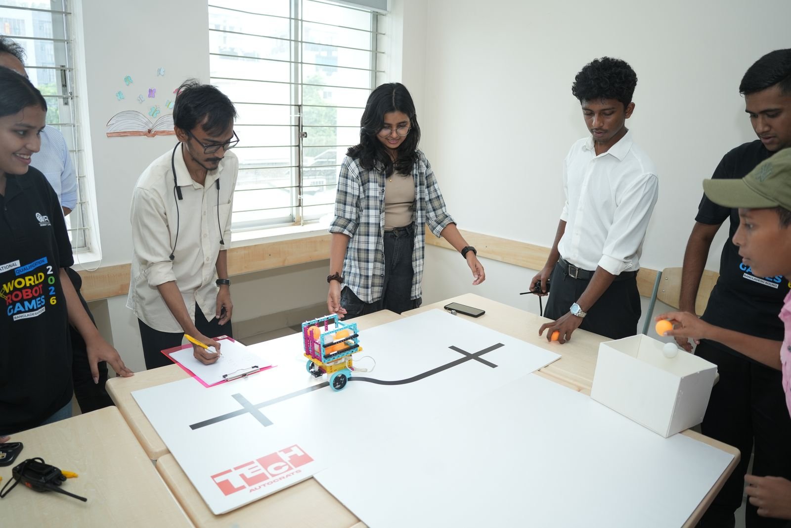 Officials record results as a small line-following robot runs across the white challenge board