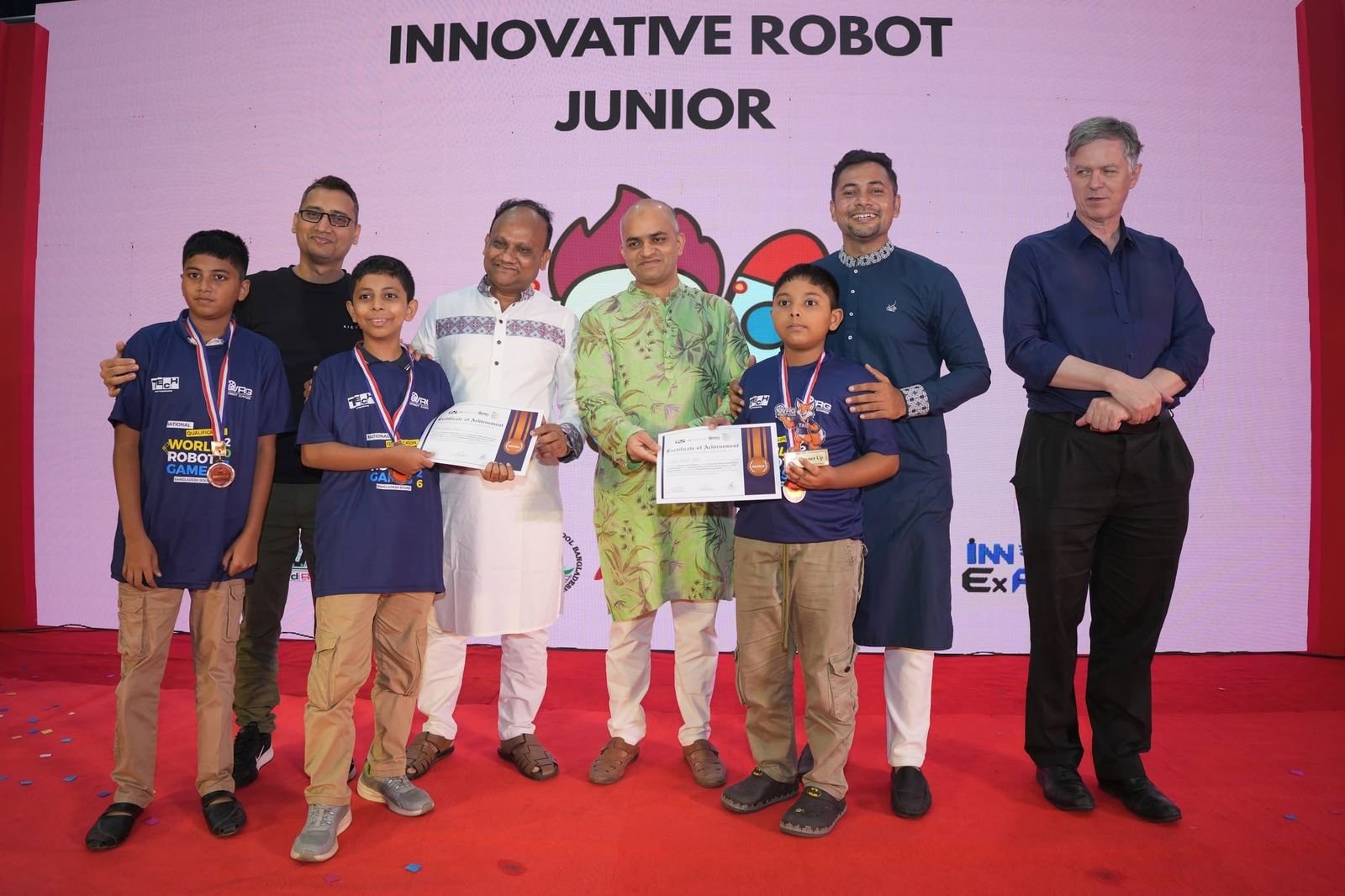 Innovative Robot Junior medalists with certificates on stage beside guests