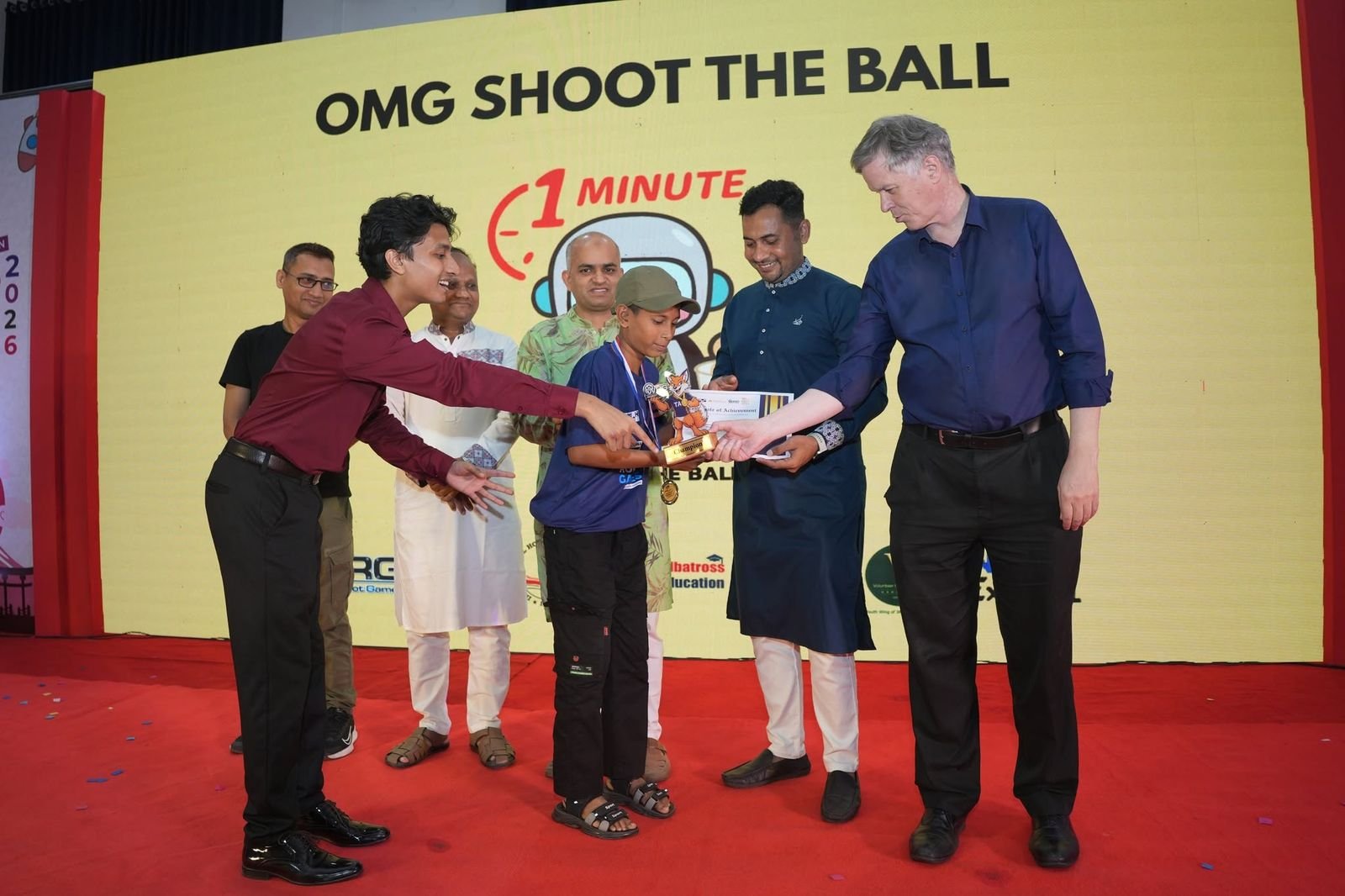 An OMG Shoot the Ball winner receives a trophy on stage