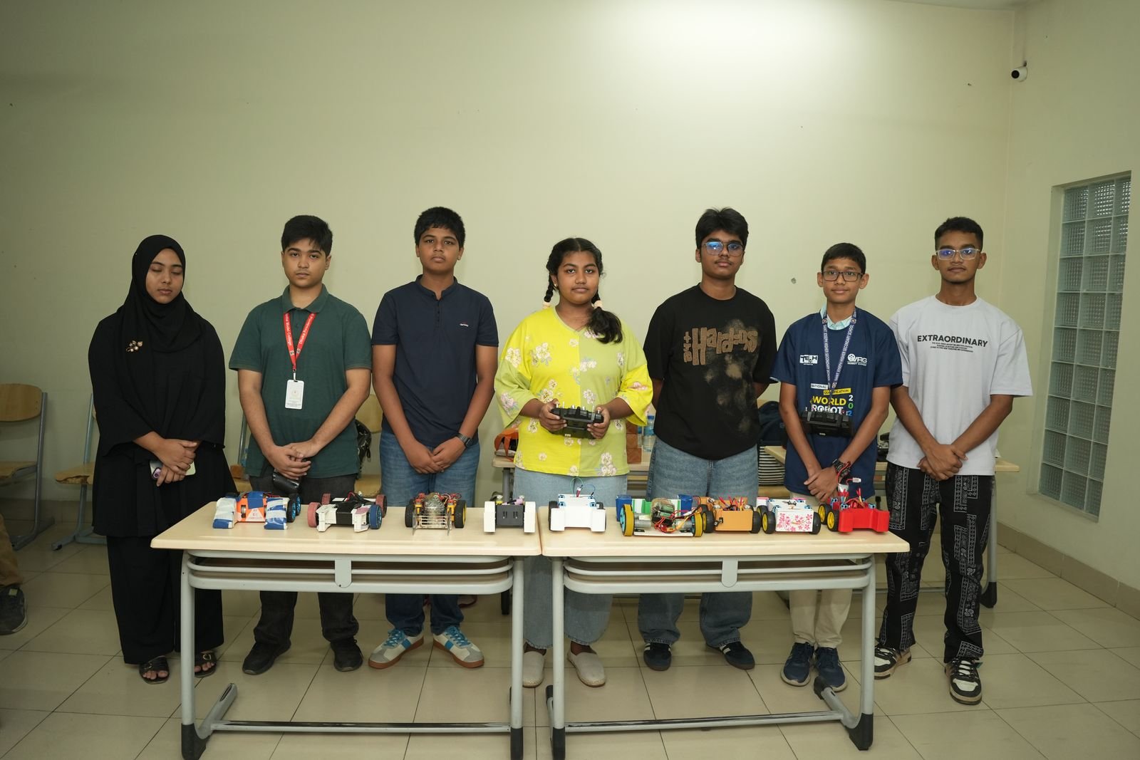 Seven participants stand behind a table of their robot cars