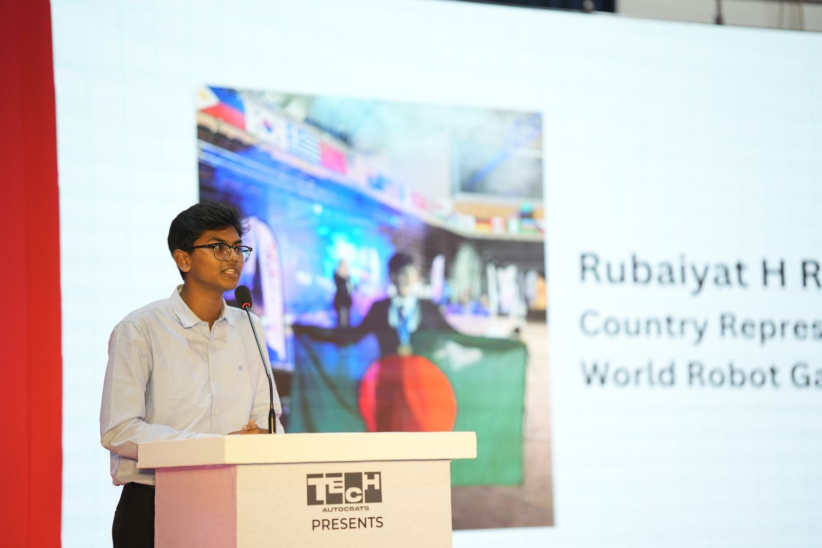 A student speaker, introduced as a World Robot Games country representative, addresses the hall